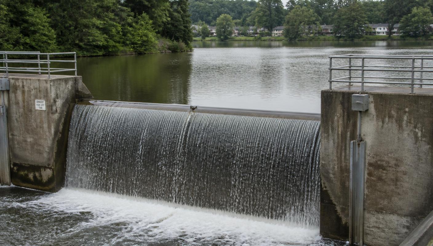 Lake Anne dam and spillway holding back a wooded lake in Reston, Virginia